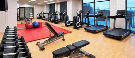 A gym with treadmills, elliptical machines, and free weights.