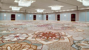 A spacious hall with a patterned carpet, multiple doors, and chandeliers. - Sheraton McKinney Hotel (McKinney)