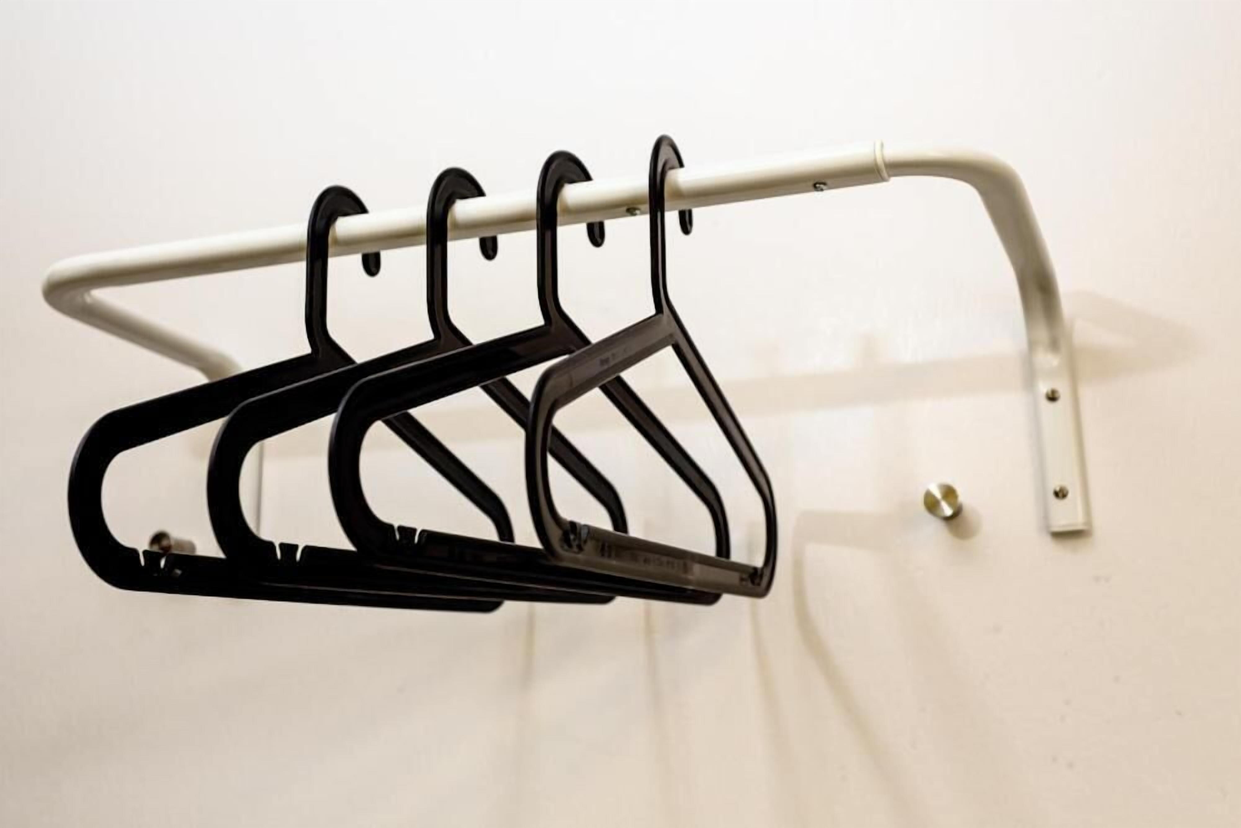 A metal coat rack with four hooks against a plain wall.