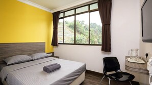A bedroom with a bed, a chair, a nightstand, and a window with curtains. - Parkland Hotel (Brinchang)