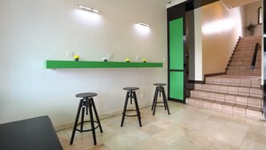 A modern interior with a green shelf, three black stools, and a staircase. - Parkland Hotel (Brinchang)