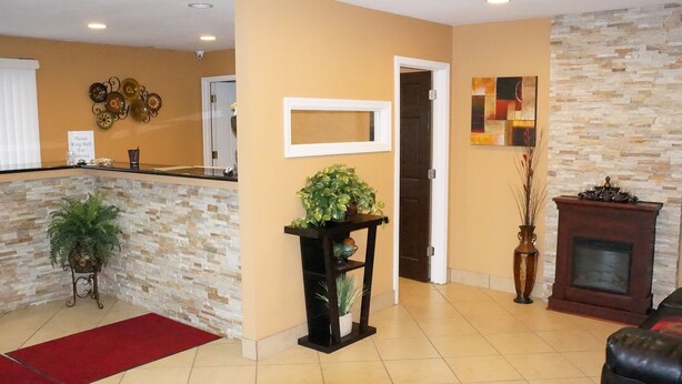 A hotel lobby with a reception desk, a stone wall, a fireplace, and a door leading to another room.