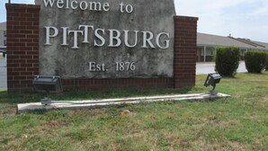 A welcome sign for Pittsburgh, established in 1876, with a brick wall and a grassy area in front.