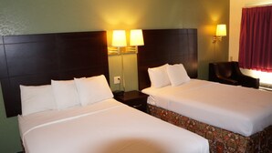A hotel room with two beds, a nightstand, a lamp, and a chair.