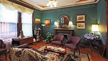 Uma sala de estar tradicional com lareira, dois poltronas, um sofá e uma mesa de centro.