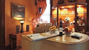 A cozy room with a wooden desk, a lamp, a bookshelf, and a painting on the wall.