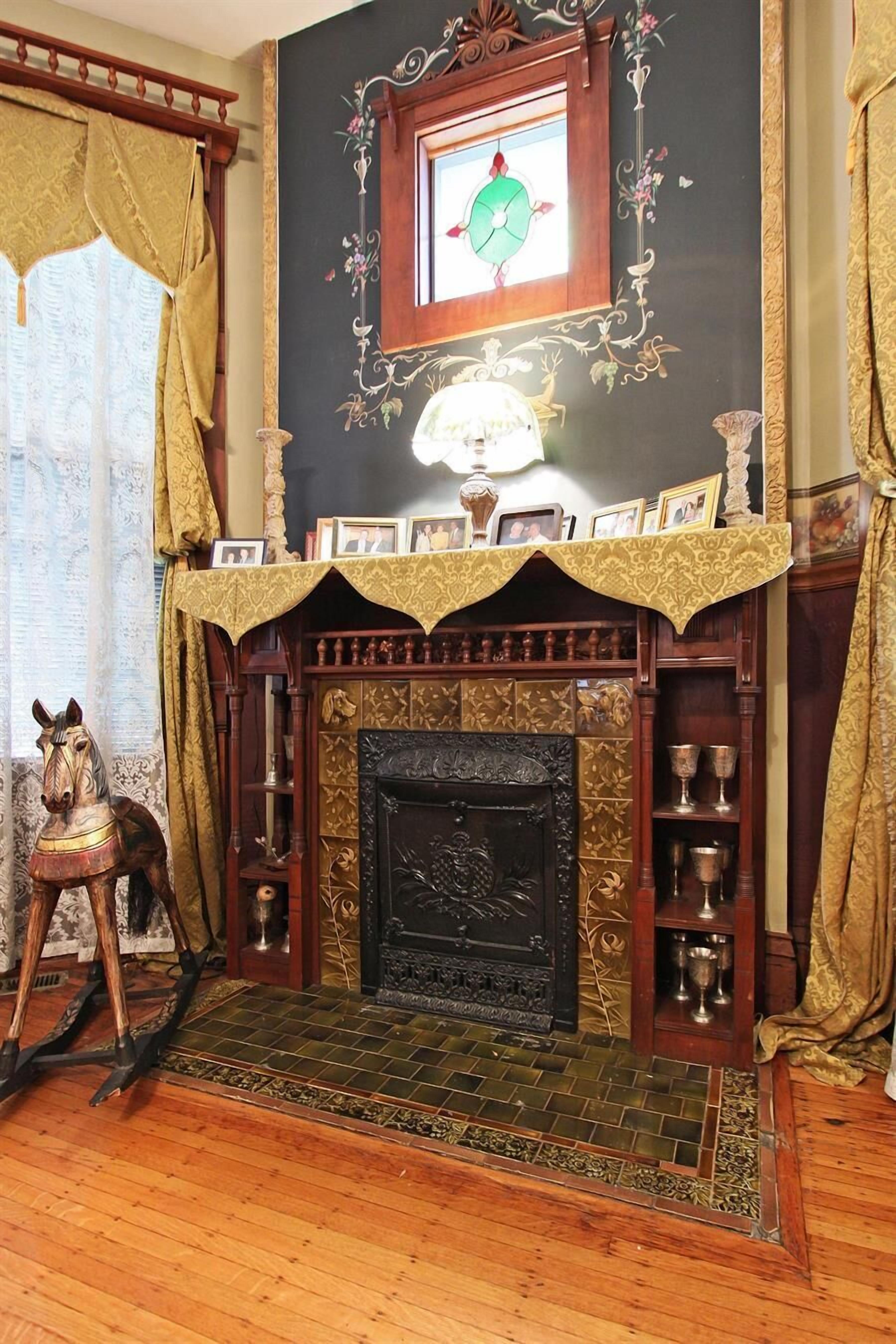 Una habitación con chimenea, una escultura de caballo de madera y un cuadro en la repisa.