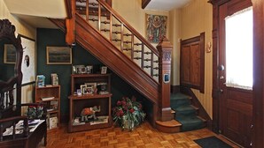 A wooden staircase with a chandelier, a door with a decorative panel, and a bookshelf with various items.
