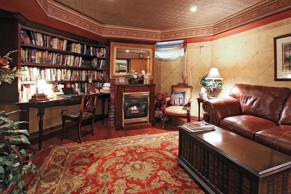 A cozy living room with a fireplace, a leather sofa, a bookshelf, and a dining area.