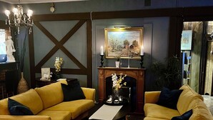 A cozy living room with two yellow sofas, a fireplace, and a chandelier. - Brunsbo G:a Biskopsgård Hotell & Konferens (Skara)