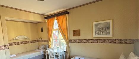A cozy room with a sofa, a small table with a vase, a desk, and a bed.