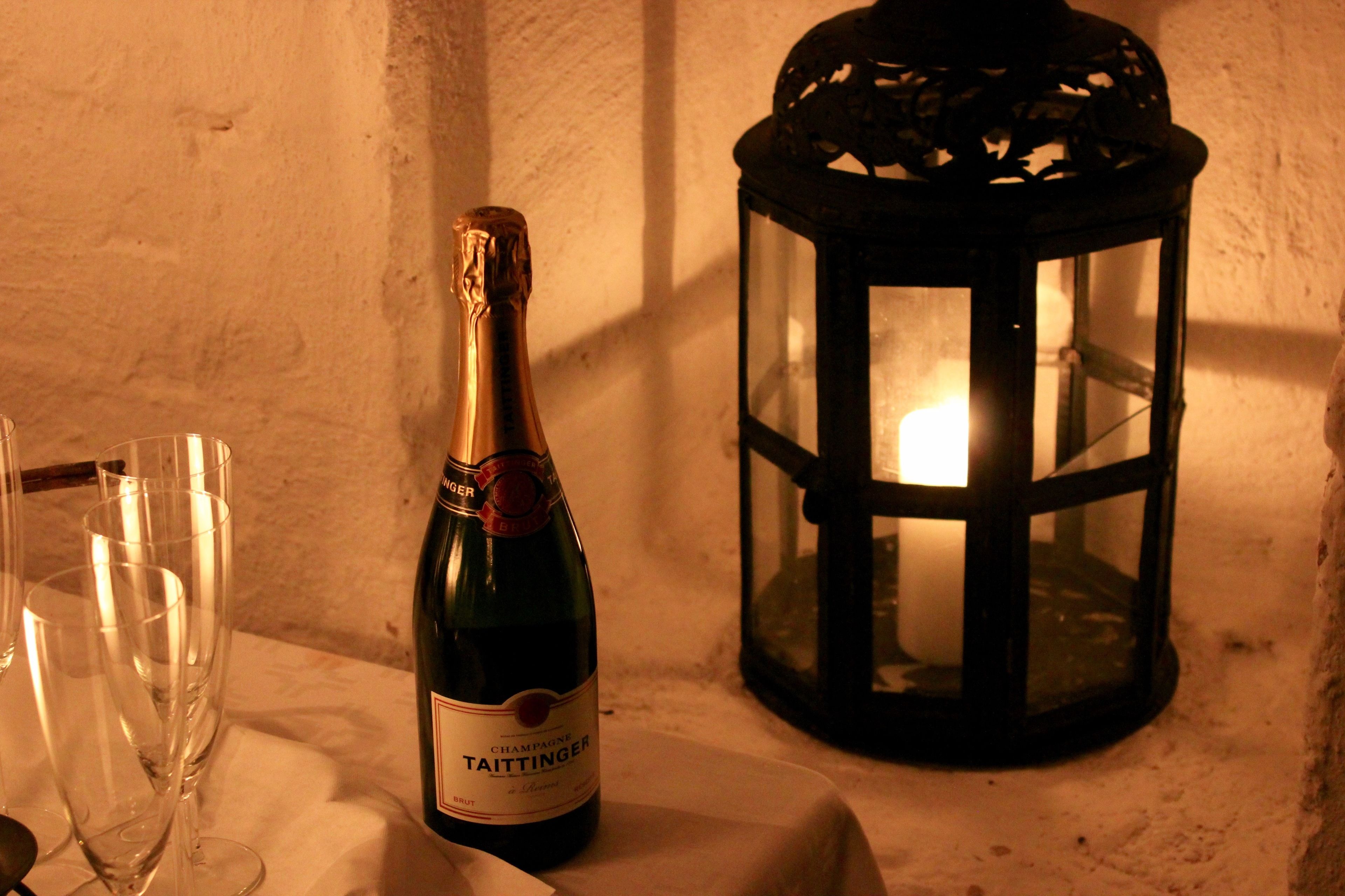 A bottle of champagne and glasses on a table next to a lantern.
