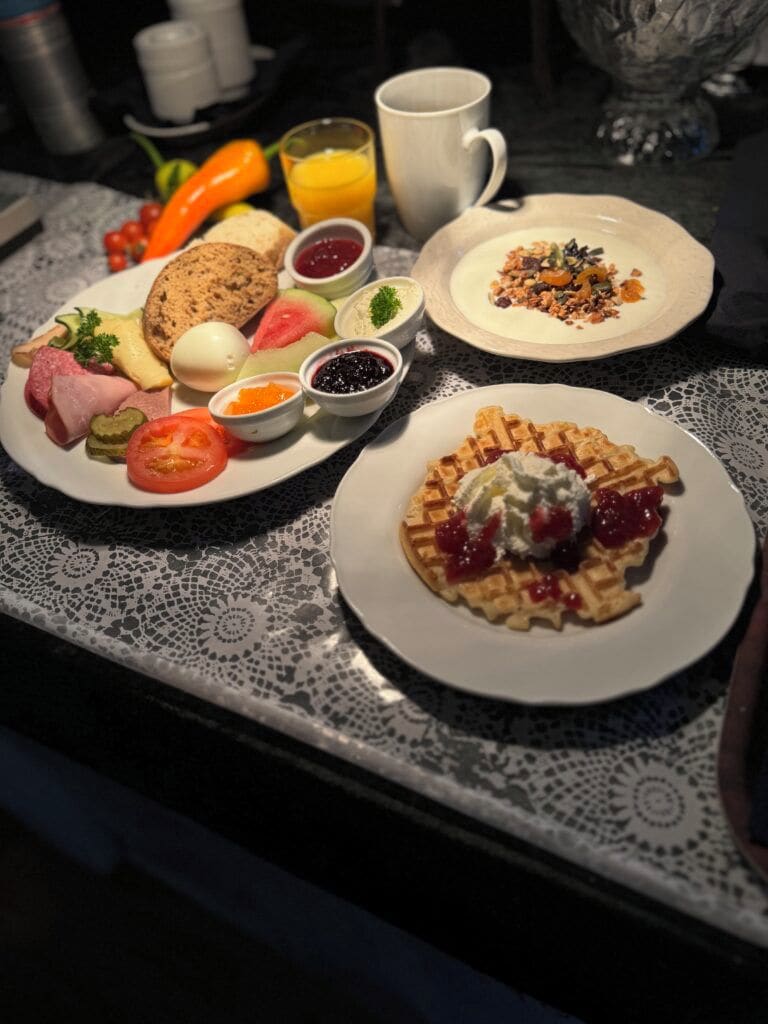 A breakfast table with various dishes including waffles, eggs, and a variety of spreads.
