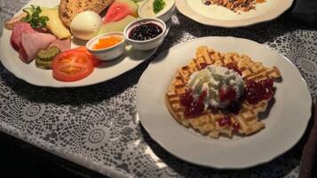 A breakfast table with various dishes including waffles, eggs, and a variety of spreads.
