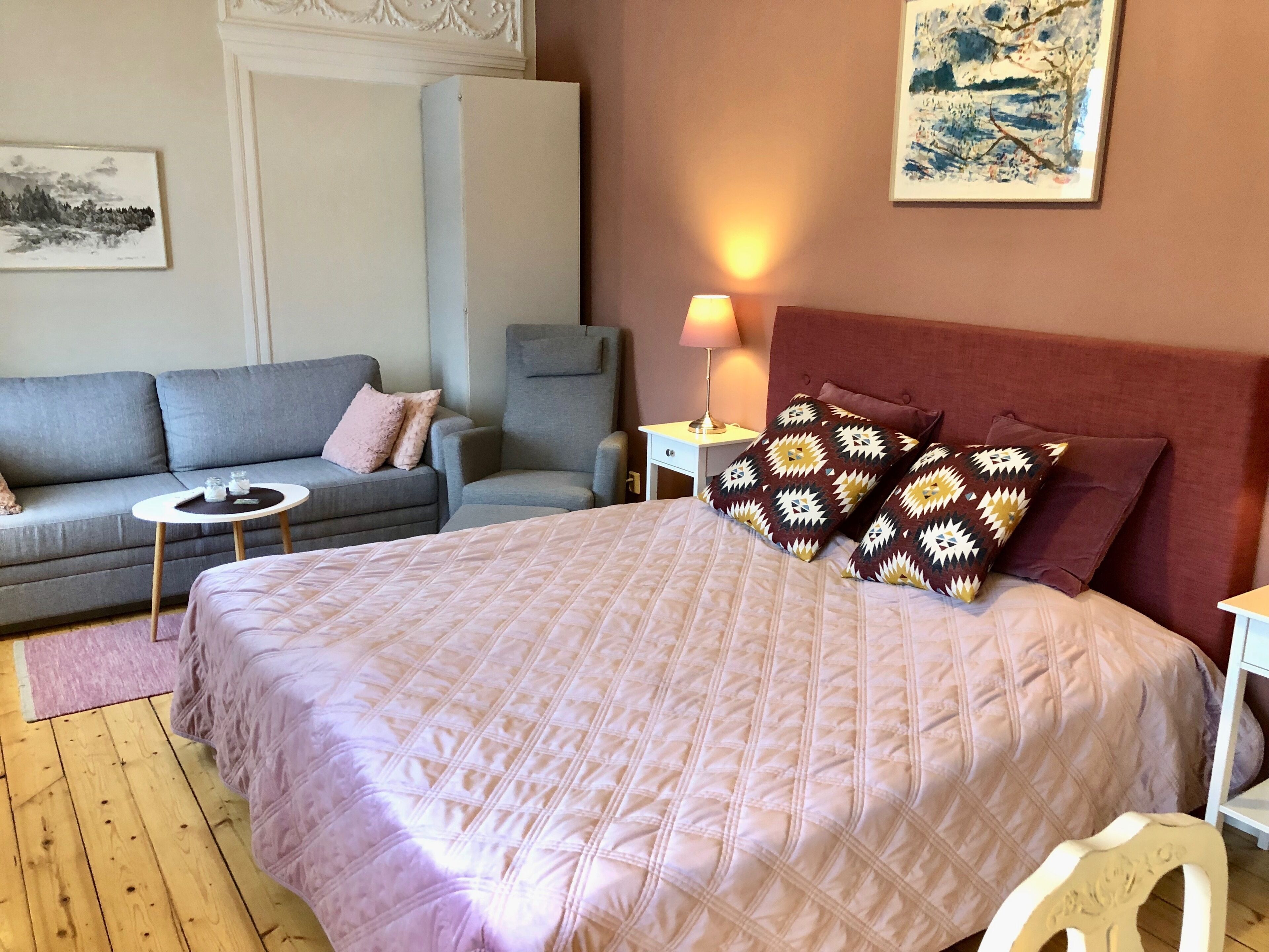 Une chambre à coucher avec un grand lit, un canapé gris, une petite table et une chaise.