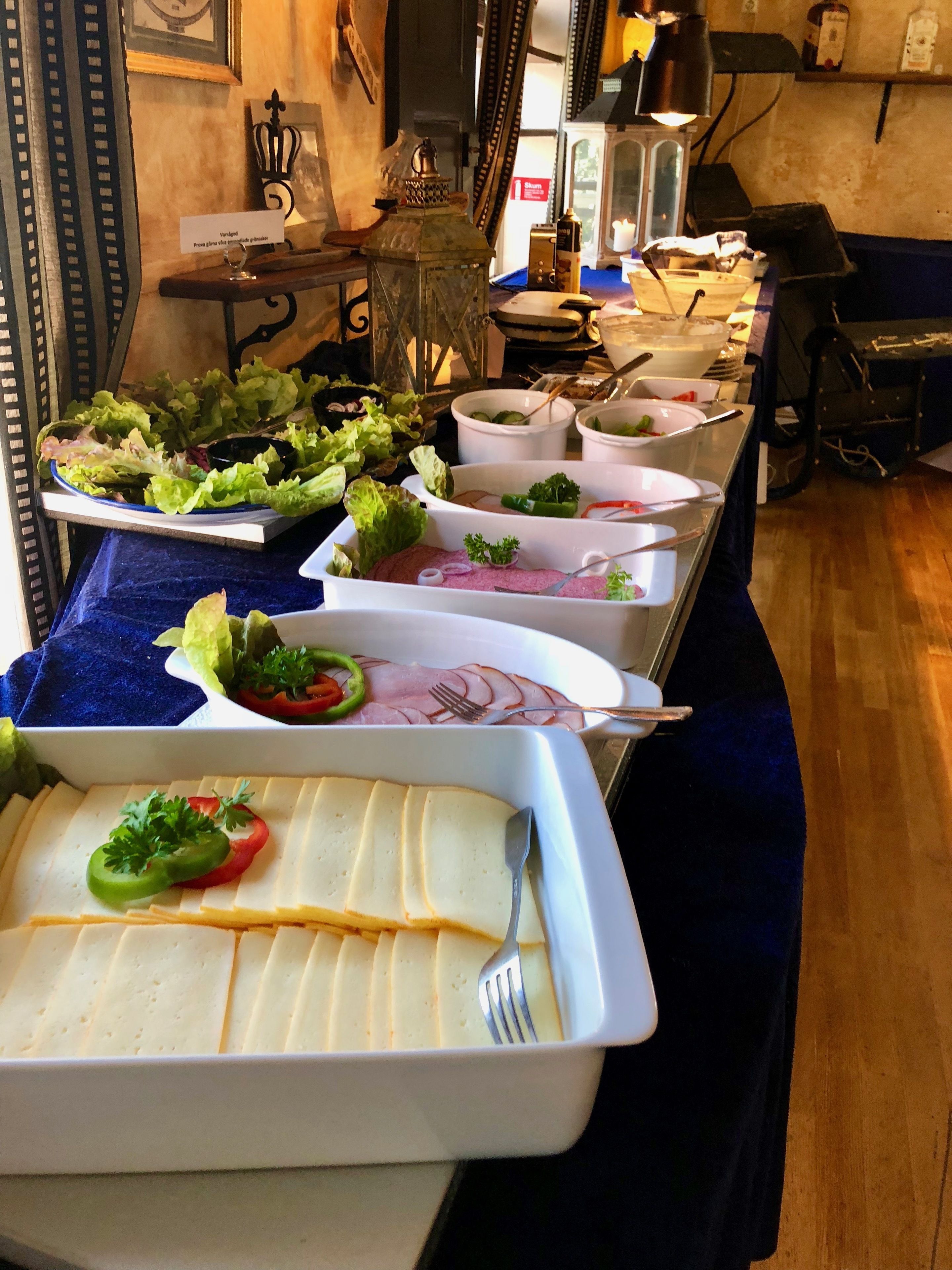 Una mesa de buffet con diversos platos, incluyendo ensaladas, carnes y quesos.