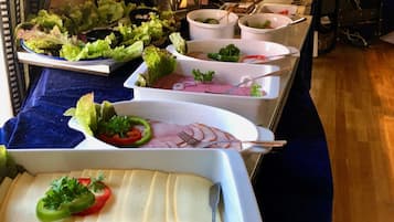 Una mesa de buffet con diversos platos, incluyendo ensaladas, carnes y quesos.