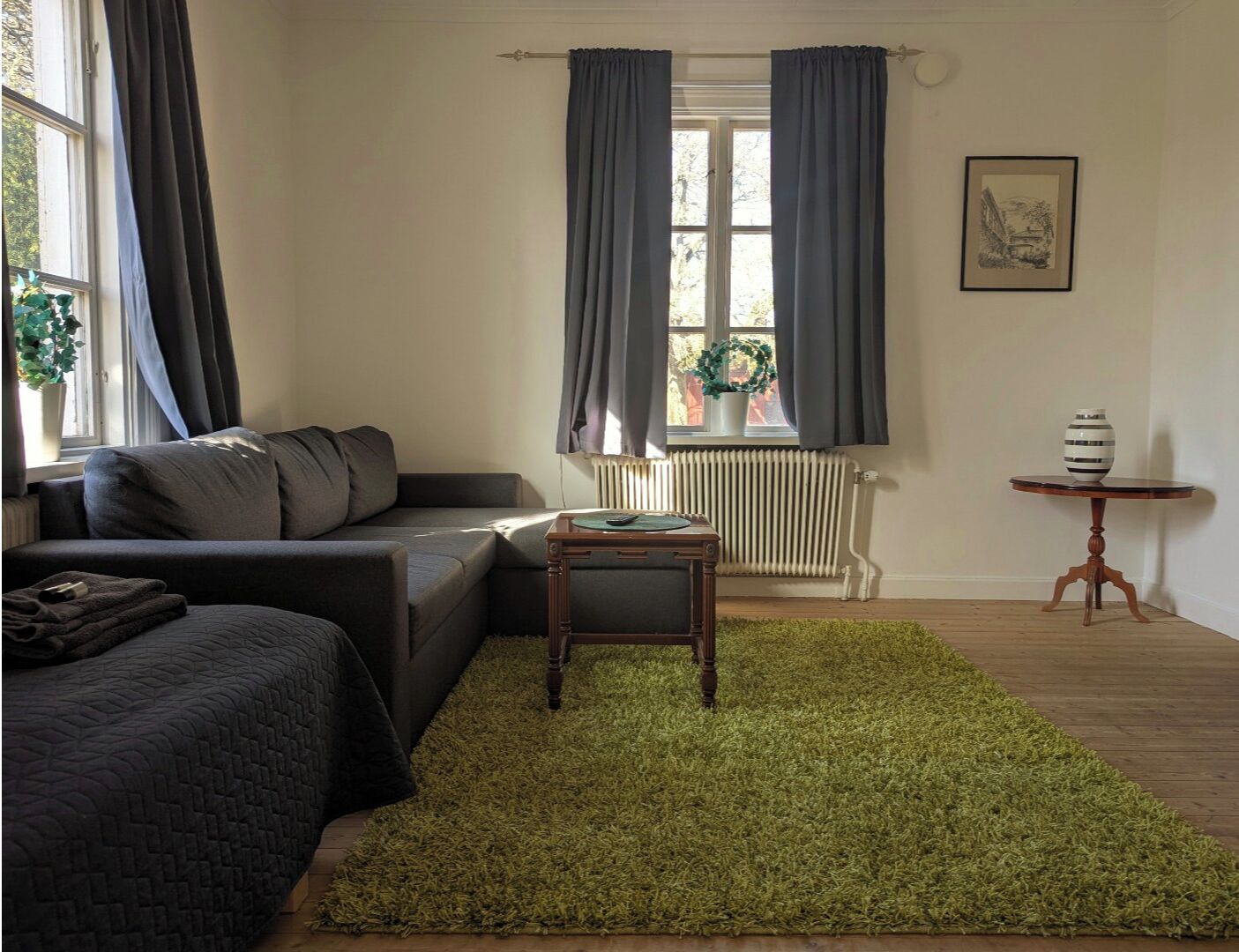 A cozy living room with a sectional sofa, a small wooden table, and a green rug.
