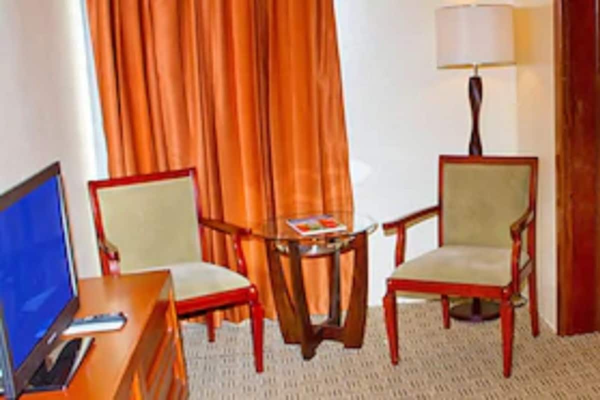 Ein Hotelzimmer mit einem Bett, einem Schreibtisch mit Stuhl, einer Lampe und einem Fernseher.