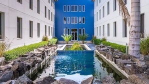 A building with a central courtyard featuring a pool, surrounded by rock formations and greenery. - Servotel (Port-au-Prince)
