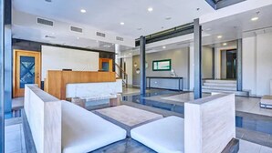 A modern lobby with a reception desk, seating area, and a staircase leading to upper floors. - Servotel (Port-au-Prince)