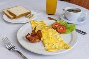 Un plato de desayuno con huevos, tocino, tostadas y una ensalada.