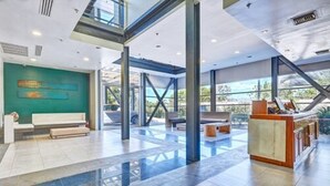 A spacious lobby with a high ceiling, large windows, and a reception desk. - Servotel (Port-au-Prince)