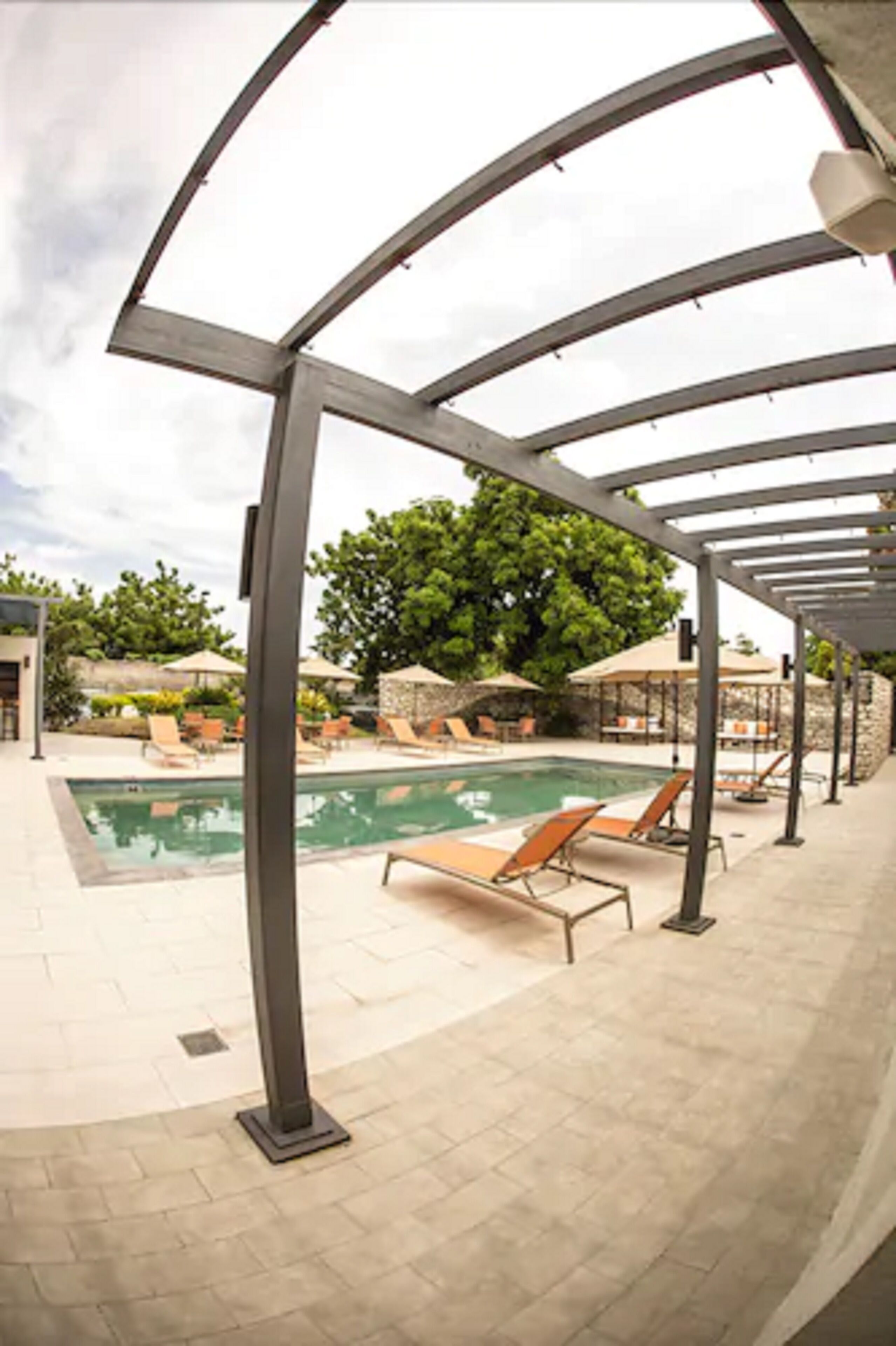 A poolside area with lounge chairs, a covered seating area, and a clear view of the pool.