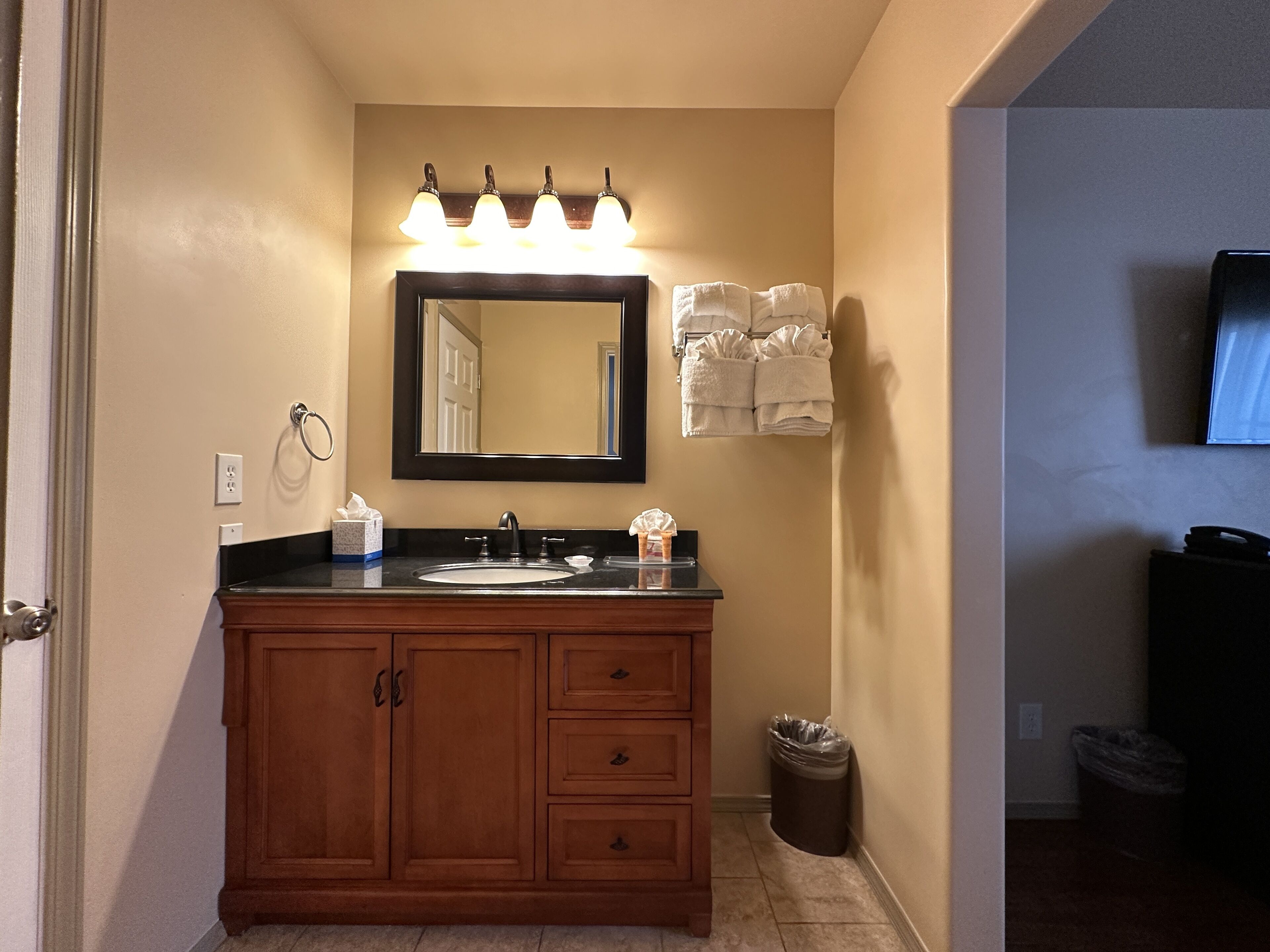 A bathroom with a wooden vanity, a mirror, a sink, and a towel rack.