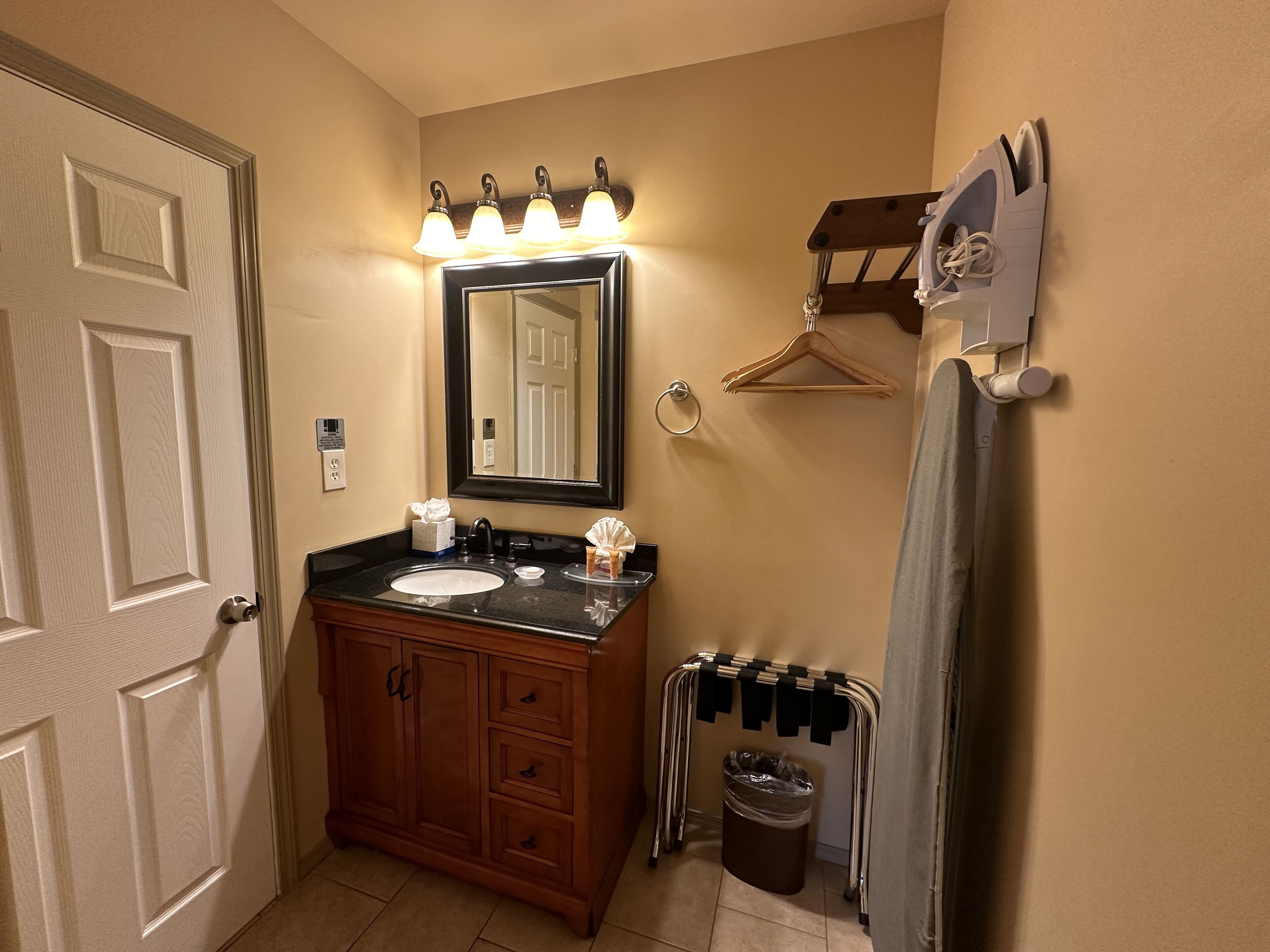 A bathroom with a vanity, sink, mirror, towel rack, and a heater.