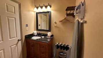 A bathroom with a vanity, sink, mirror, towel rack, and a heater.