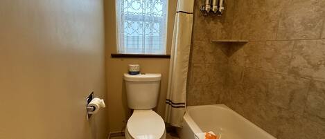 Un baño con inodoro, una ventana con cortina, ducha y bañera.