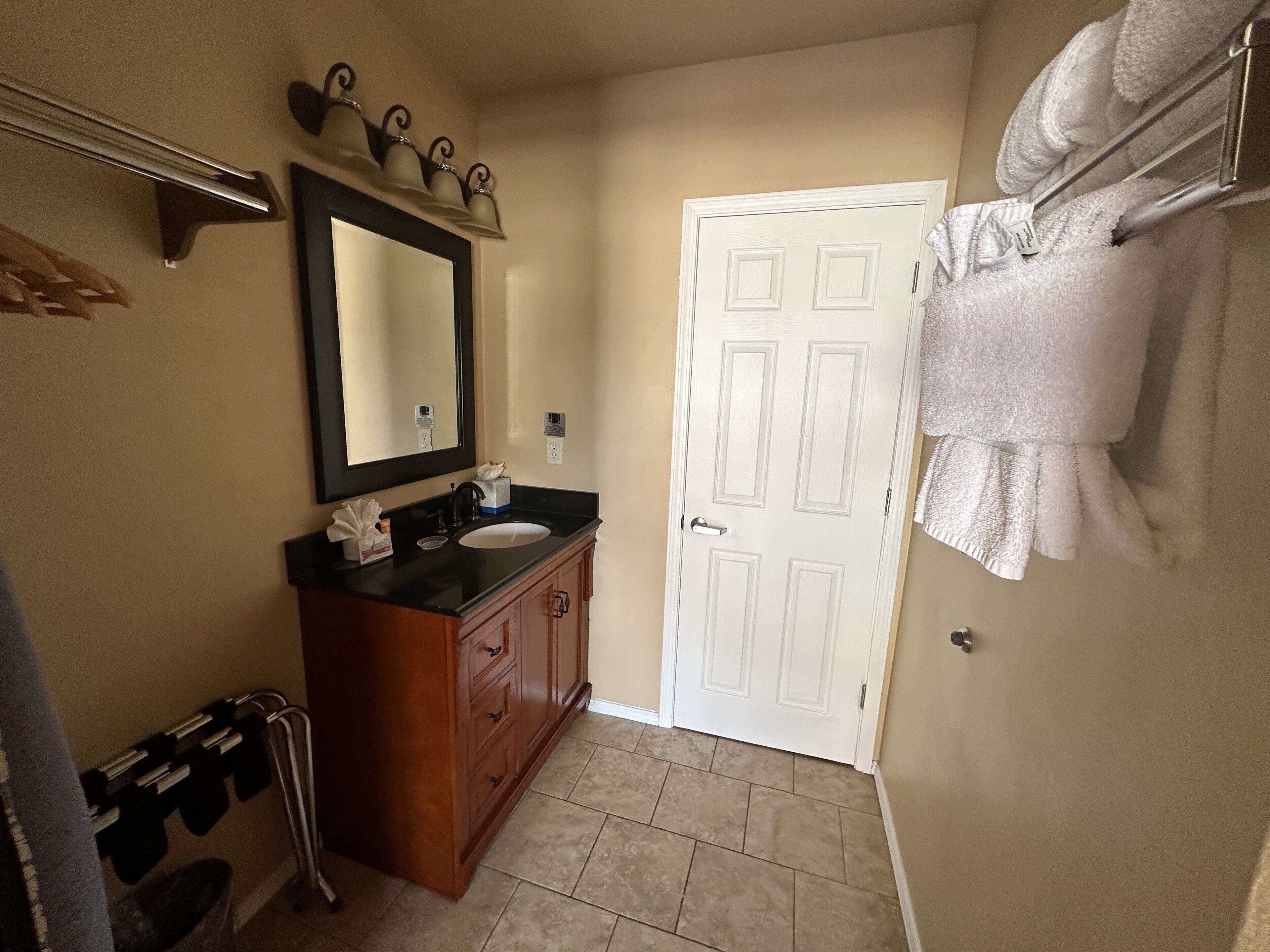 A bathroom with a sink, mirror, towel rack, and a door.