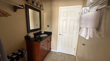 Une salle de bain avec un lavabo, un miroir, un porte-serviettes et une porte.