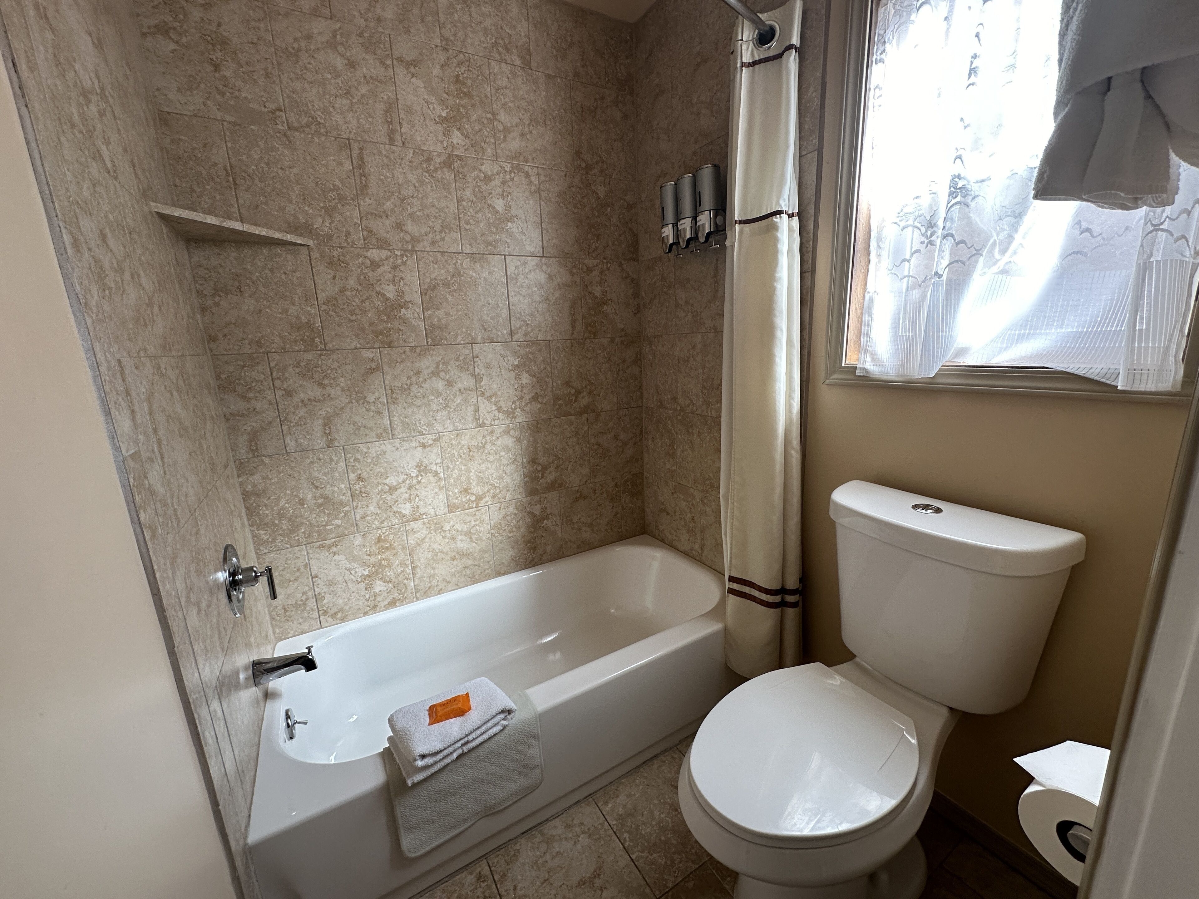 A bathroom with a bathtub, toilet, and shower curtain.