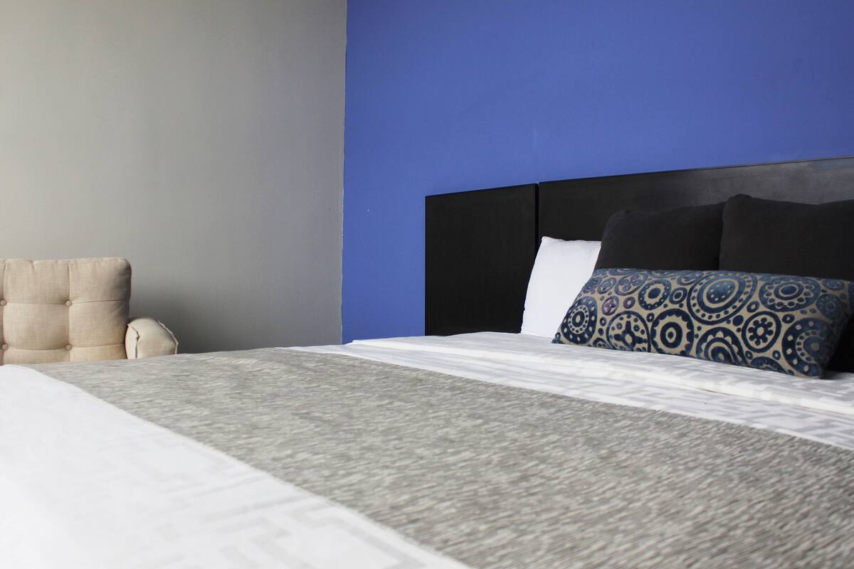A modern bedroom with a bed, a headboard, and a chair.