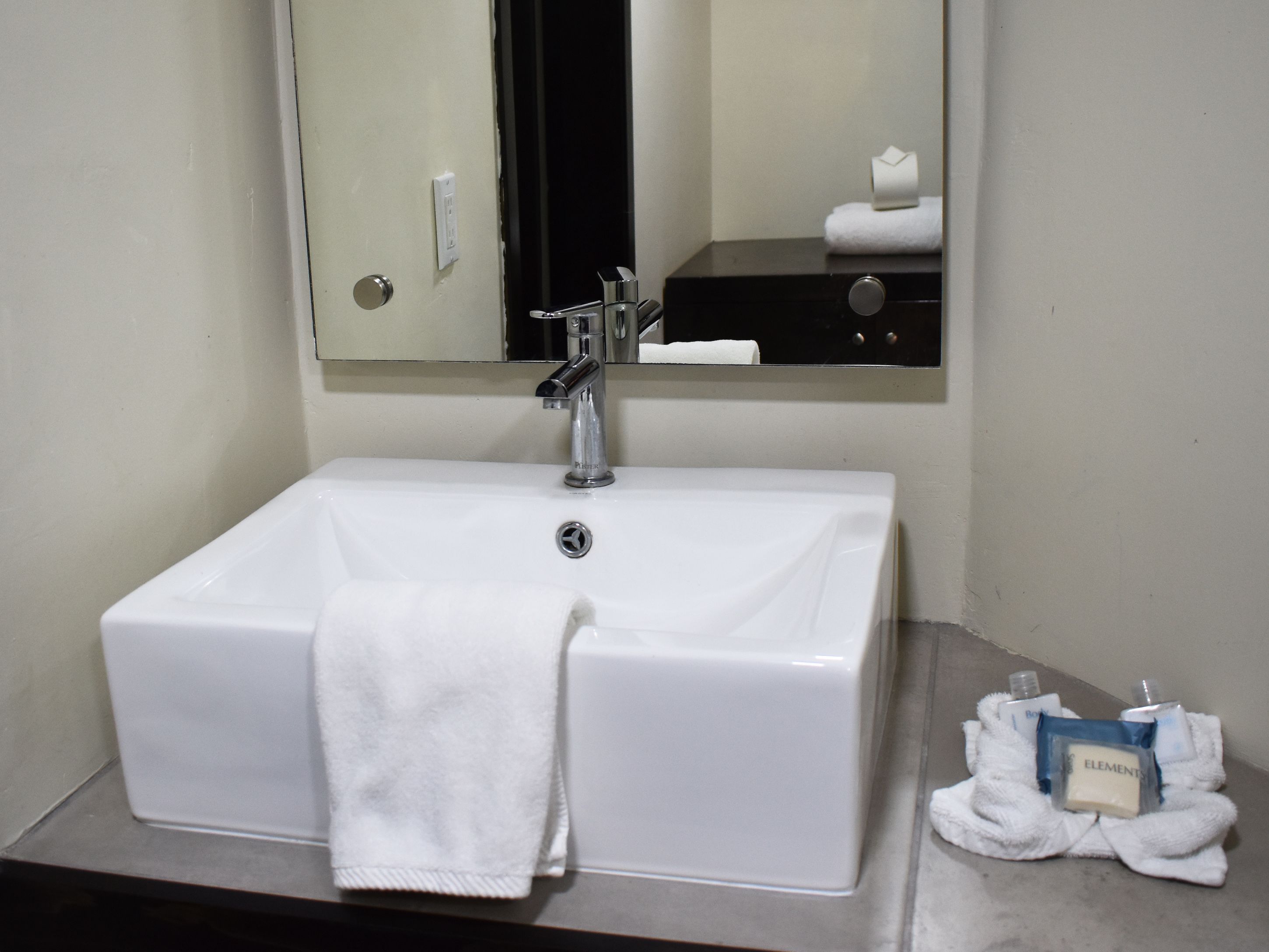 A bathroom with a white sink, a mirror, and a towel rack.