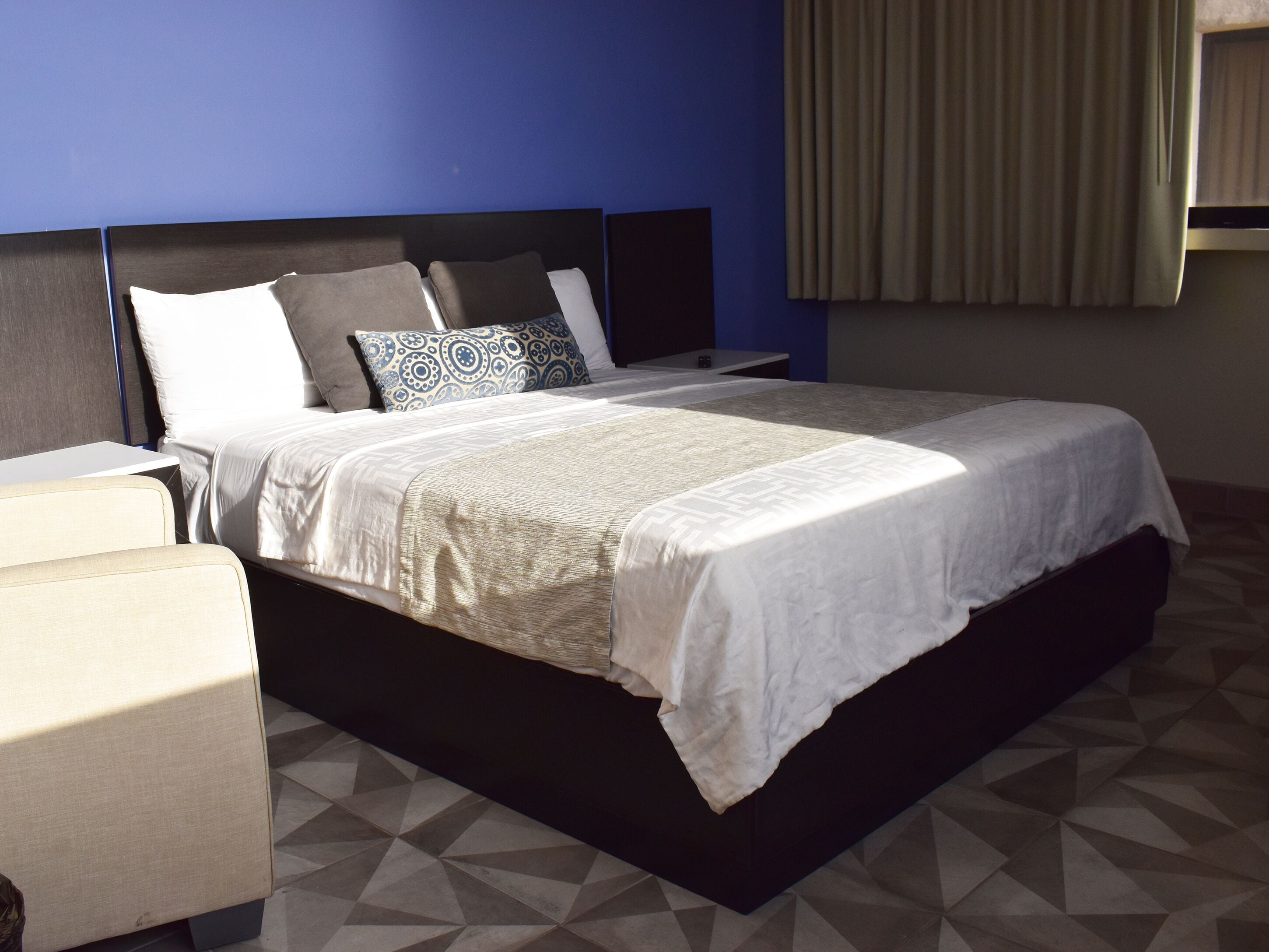 A modern hotel room with a large bed, a nightstand, and a seating area.