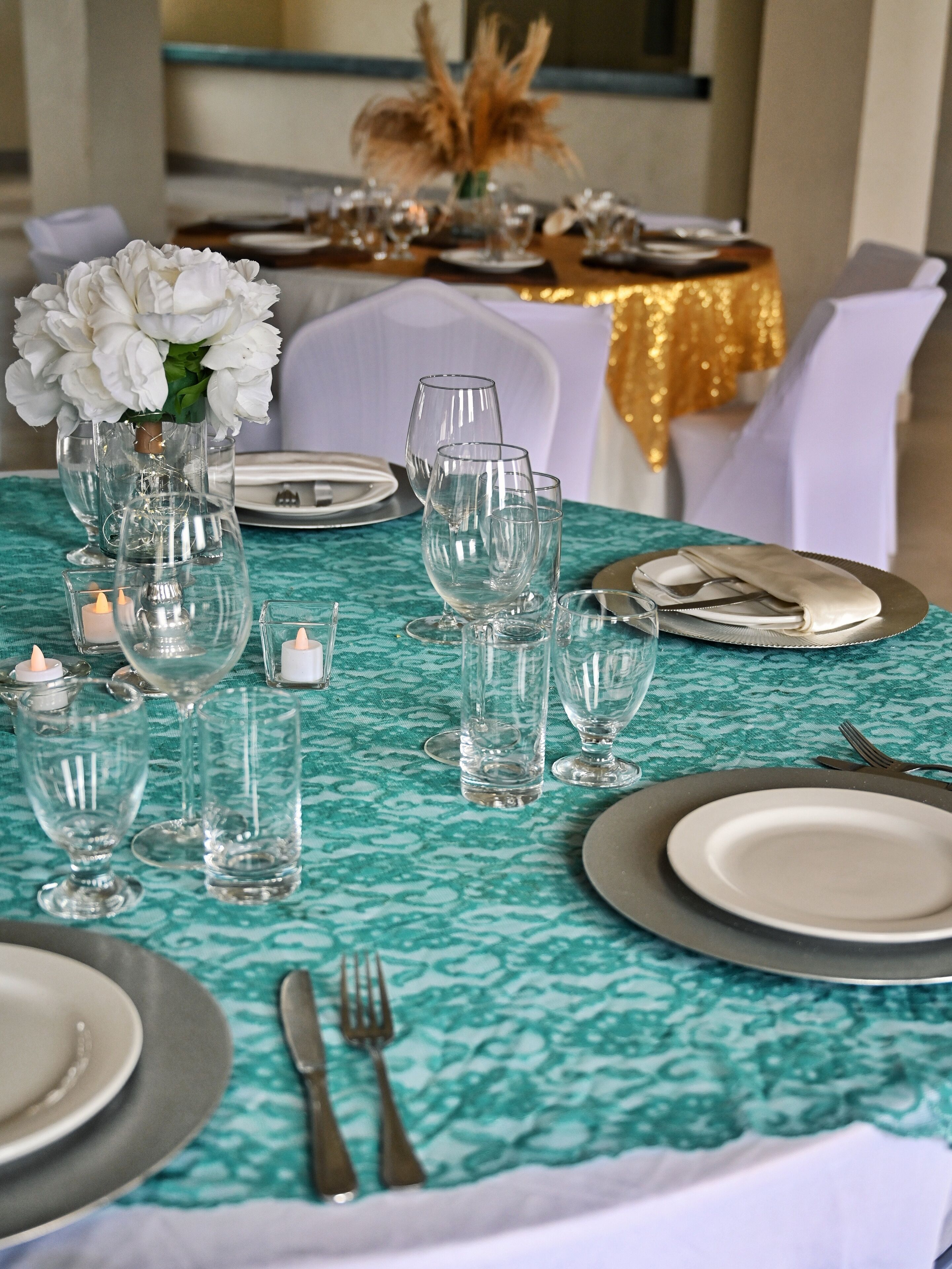 A table set for a formal event with clear glassware, candles, and a white floral arrangement.