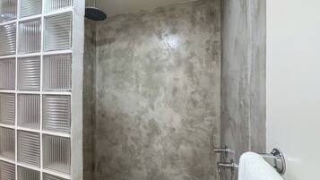 Une douche avec un mur texturé, une porte en verre et un porte-serviettes.