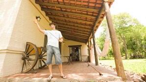 A man standing under a covered patio with a hammock and a wooden cart. - Golden Lodge (Paso de la Patria)