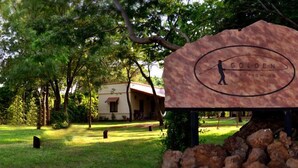 A sign for 'Golden' with a silhouette of a person fishing, surrounded by trees and a building in the background. - Golden Lodge (Paso de la Patria)