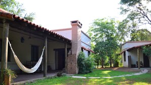 A house with a covered porch, a hammock, and a well-maintained lawn. - Golden Lodge (Paso de la Patria)
