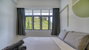 Habitación de hotel con una cama grande, una ventana con cortinas y vistas a zonas verdes.