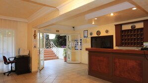 A reception area with a desk, computer, and a staircase leading to an outdoor area. - Amaris Apartments (Marmaris)