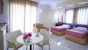 A hotel room with two beds, a dining table with chairs, a sofa, and a kitchenette. - Amaris Apartments (Marmaris)