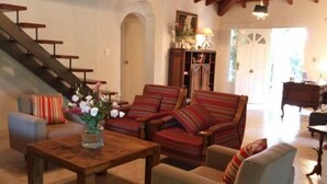 A living room with a staircase, a wooden coffee table, striped armchairs, and a sofa. - Angelo di Caneva (Chacras de Coria)