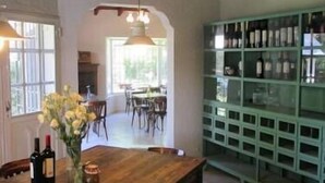 A dining area with a wooden table, chairs, a vase of flowers, and a wine rack. - Angelo di Caneva (Chacras de Coria)