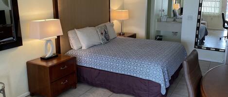 A hotel room with a large bed, two bedside tables, a chair, a desk, and a mirror.