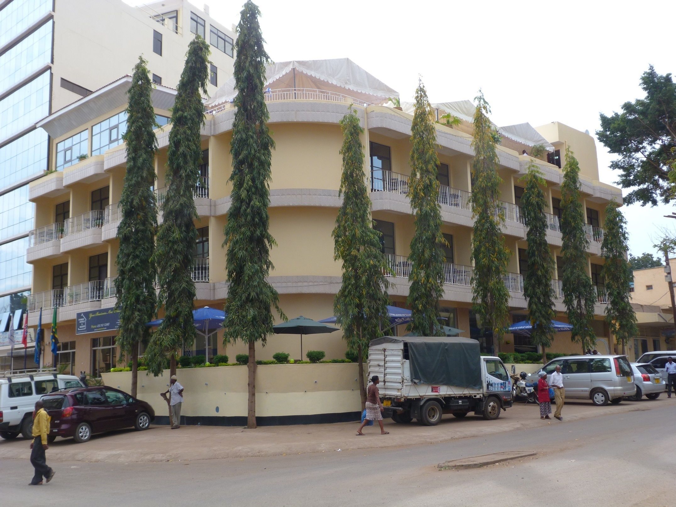 A multi-story hotel with balconies, outdoor seating, and a parked truck.